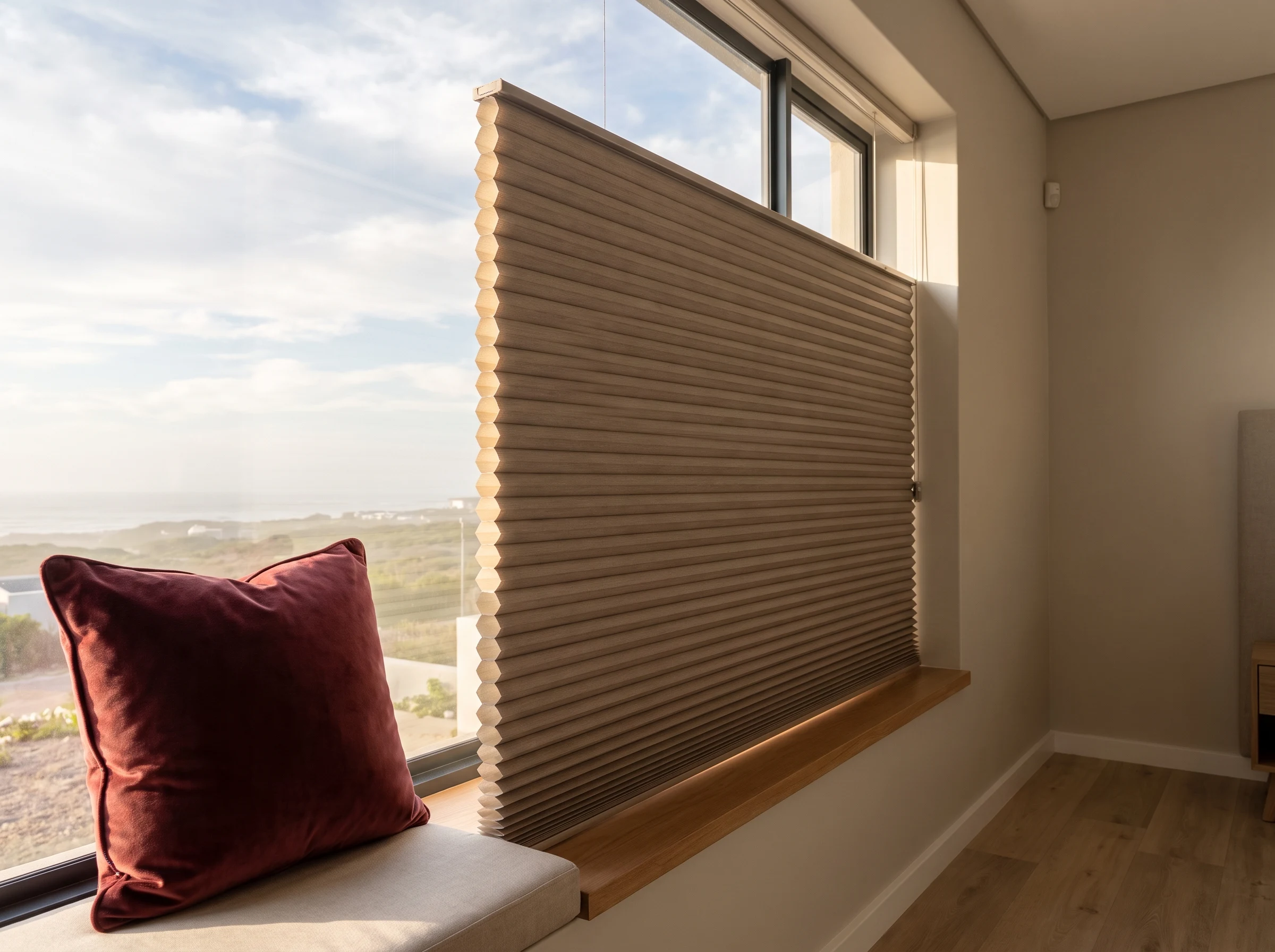 Taupe cellular honeycomb blind on a Sunningdale window seat with an oxblood cushion in the sun